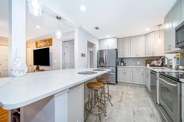 a kitchen with stainless steel appliances kitchen island granite countertop a stove a sink and a refrigerator