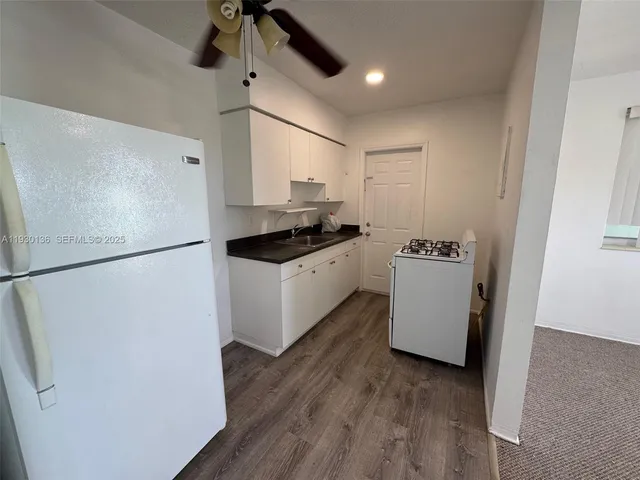 a kitchen with sink a refrigerator and white cabinets