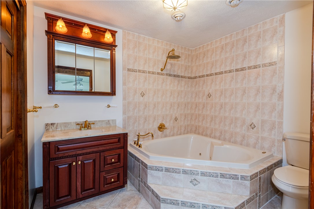 6750 Little Twin Road Germantown, OH 45327 - Photo 22 of 88 This bathroom features a large corner tub, a vanity with a stone countertop, and tiled walls.