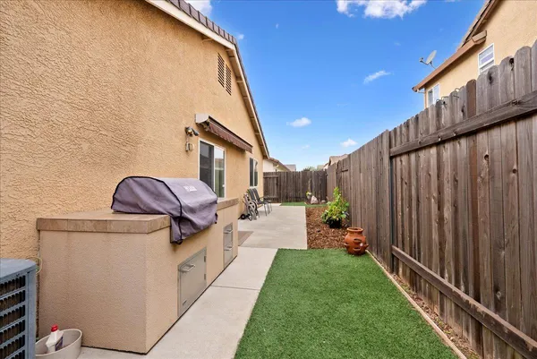 a backyard of a house with wooden fence and chairs