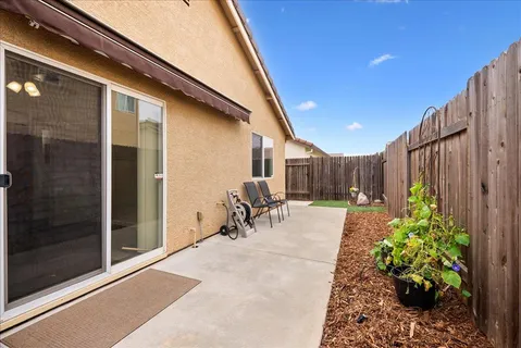 a patio with table and chairs and potted plants