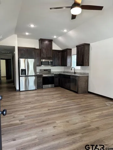 a large kitchen with stainless steel appliances a large counter top a stove and a refrigerator