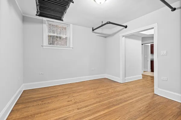 a view of an empty room with wooden floor and a ceiling fan