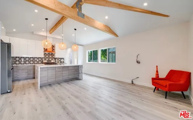 a kitchen with stainless steel appliances kitchen island granite countertop a stove a sink and a refrigerator with wooden floors