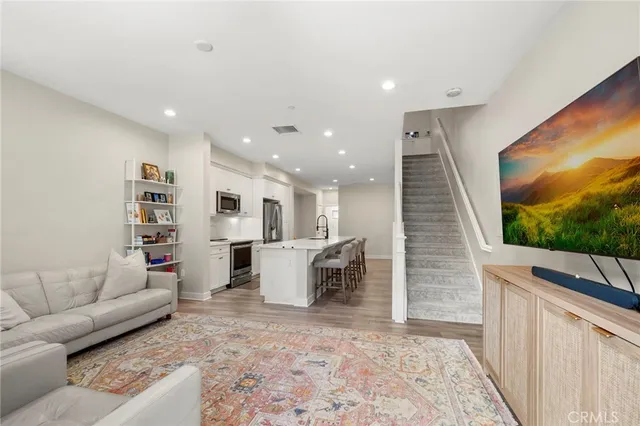 a living room with furniture a flat screen tv and kitchen view