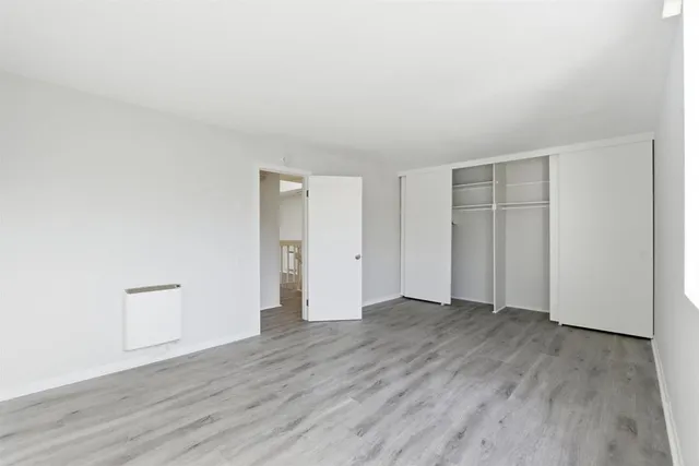 a view of an empty room with wooden floor and closet
