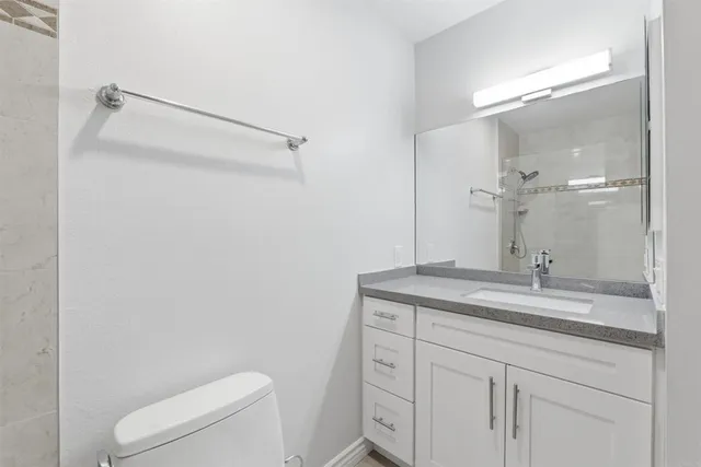 a bathroom with a granite countertop sink a toilet and a mirror