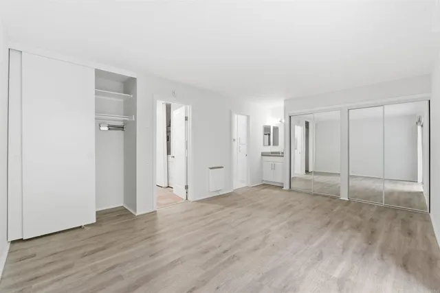 a view of an empty room with wooden floor & closet