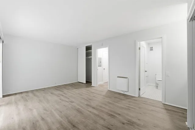 a view of an empty room with wooden floor and bathroom