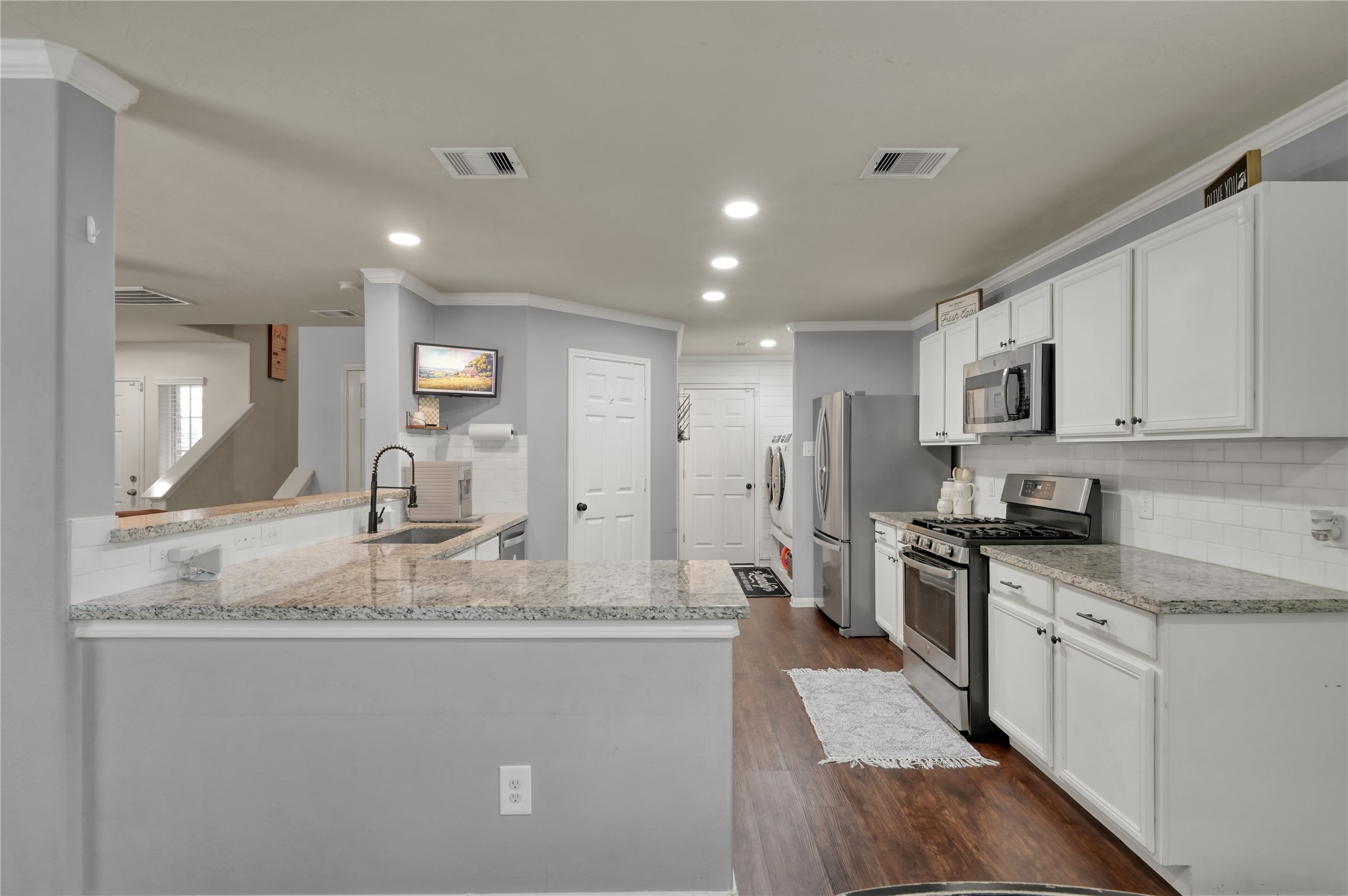 21610 Falvel Misty Drive Spring, TX 77388 - Photo 6 of 28 Extensive kitchen renovations including granite countertops, stainless steel appliances, painted cabinetry, undermount sink, and luxury vinyl flooring throughout the main living areas