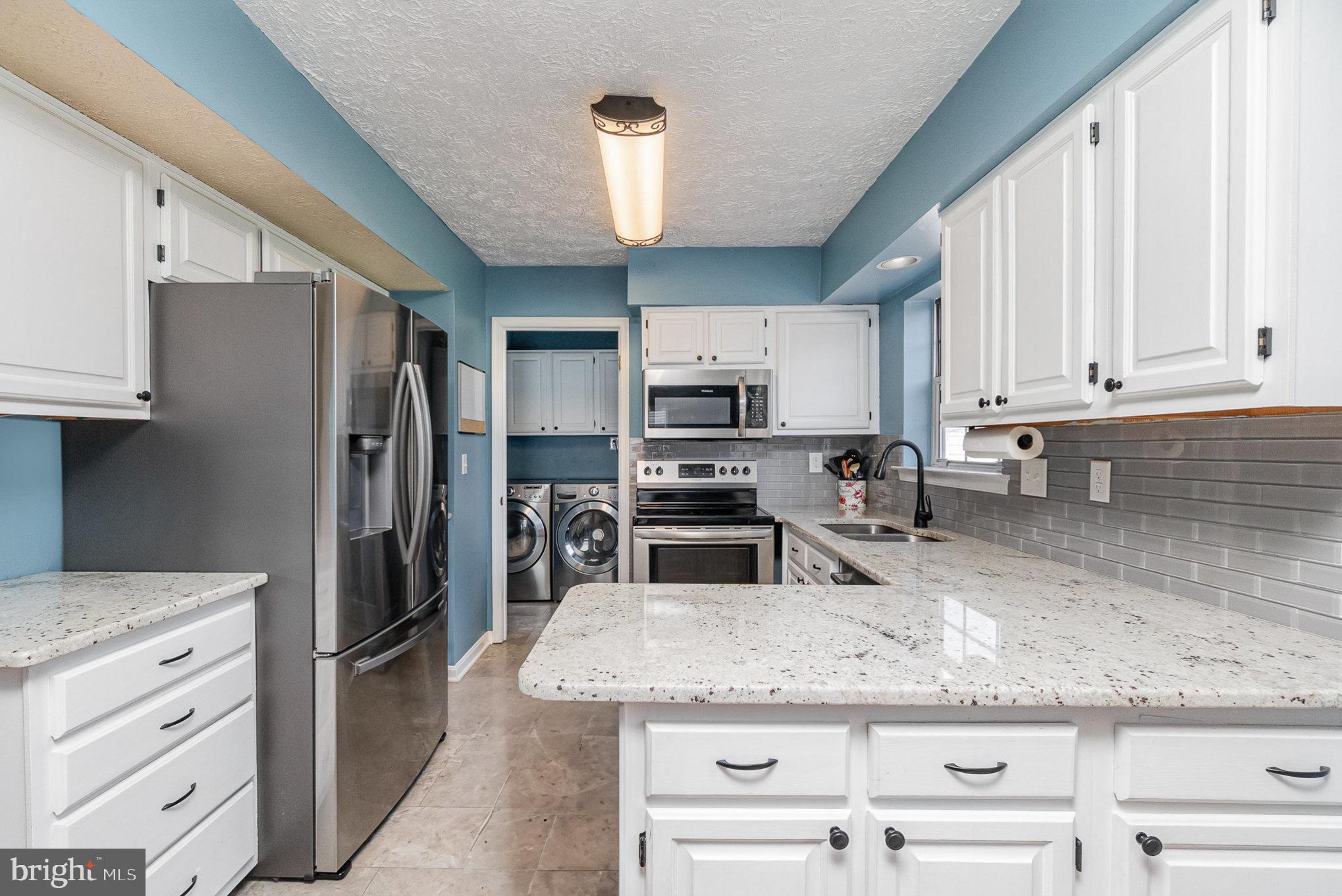 a kitchen with granite countertop a refrigerator stove and kitchen island