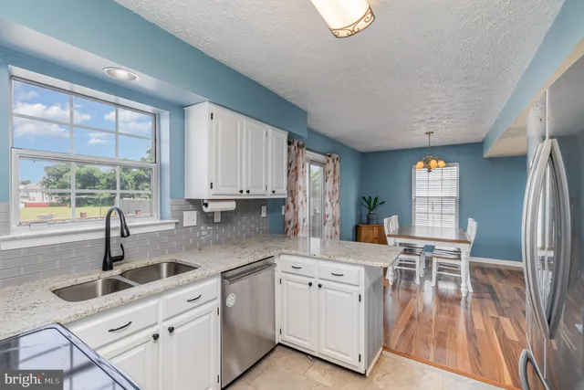 a kitchen with granite countertop white cabinets and wooden floors