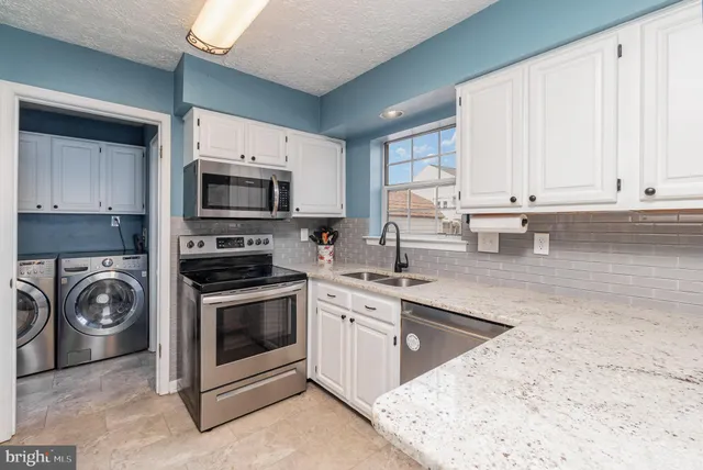 a kitchen with granite countertop a stove a sink and a microwave