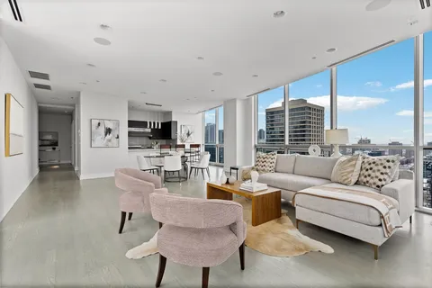 a living room with furniture kitchen view and a large window