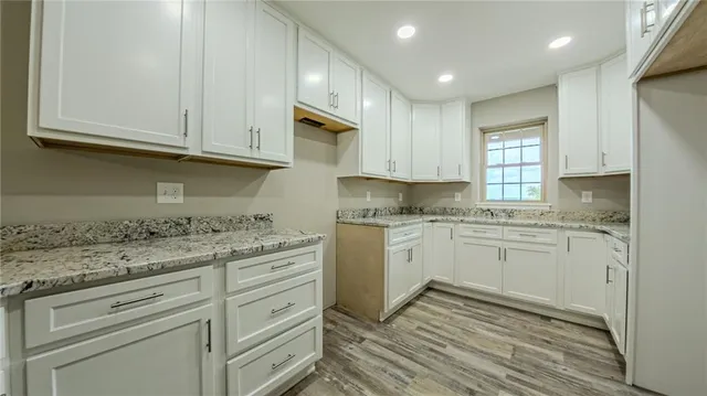 a kitchen with granite countertop white cabinets and white appliances