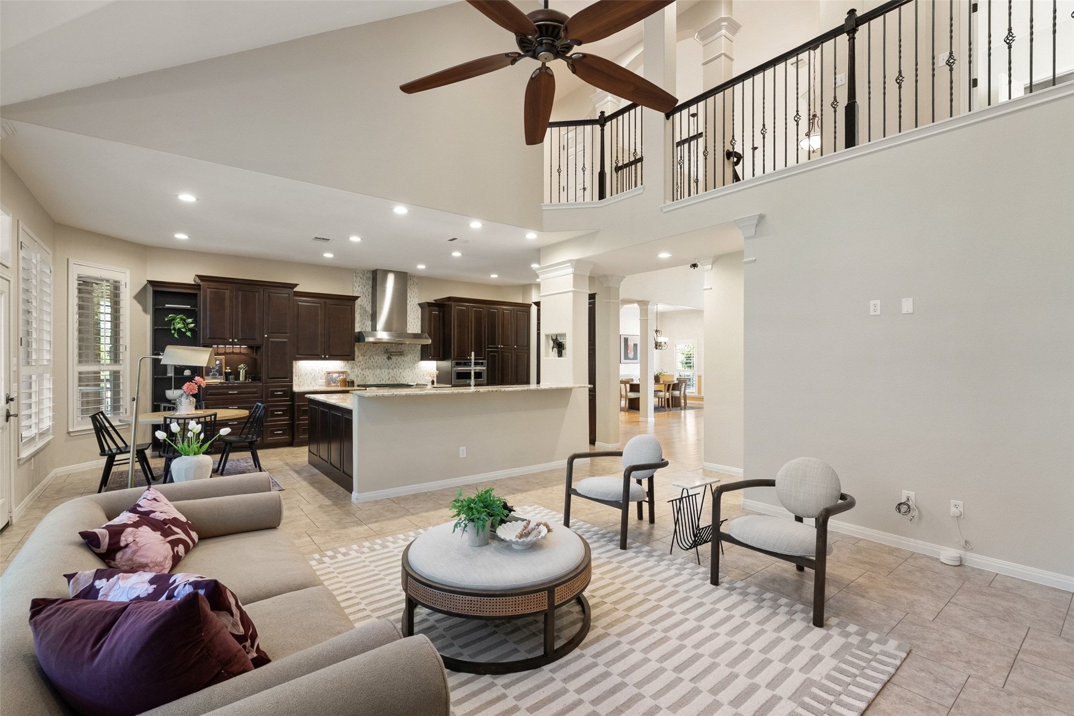 8215 Dark Ridge Cove Austin, TX 78737 - Photo 12 of 40 An airy main living room seamlessly connects to dining and kitchen spaces, bathed in natural light from tall windows framed by plantation shutters.