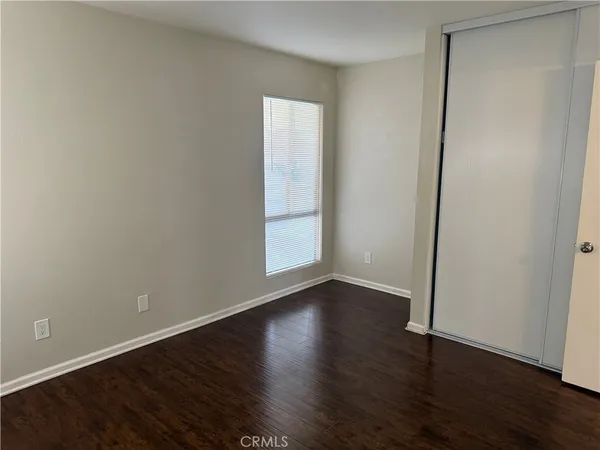 an empty room with wooden floor and closet area