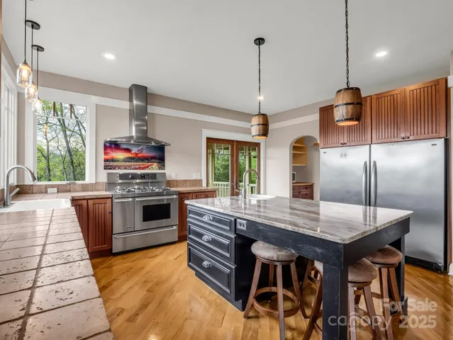 a kitchen with stainless steel appliances granite countertop a sink a stove and a wooden floors