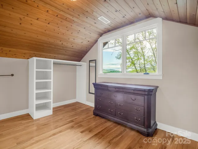 an empty room with wooden floor closet and windows