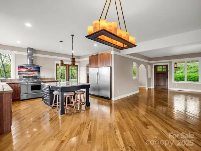 an open kitchen with wooden floor and stainless steel appliances