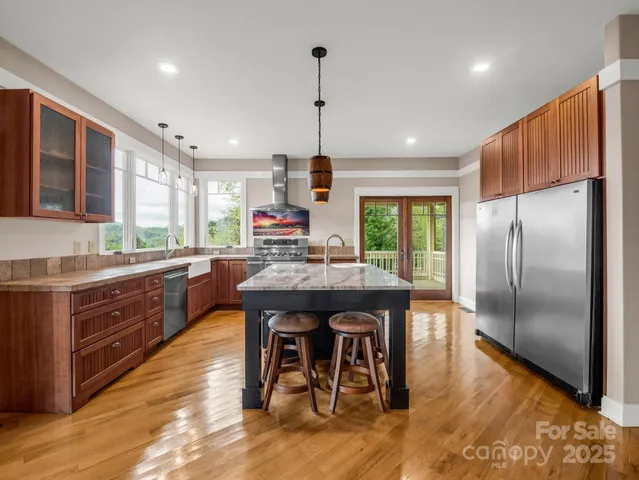 a kitchen with stainless steel appliances granite countertop a table chairs sink refrigerator and microwave