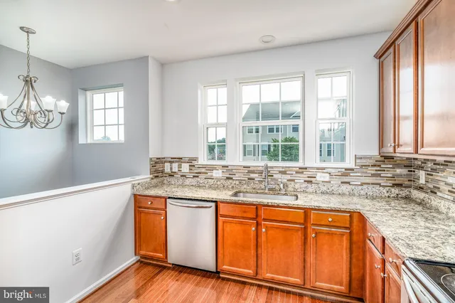 a kitchen with stainless steel appliances granite countertop wooden cabinets and a large window