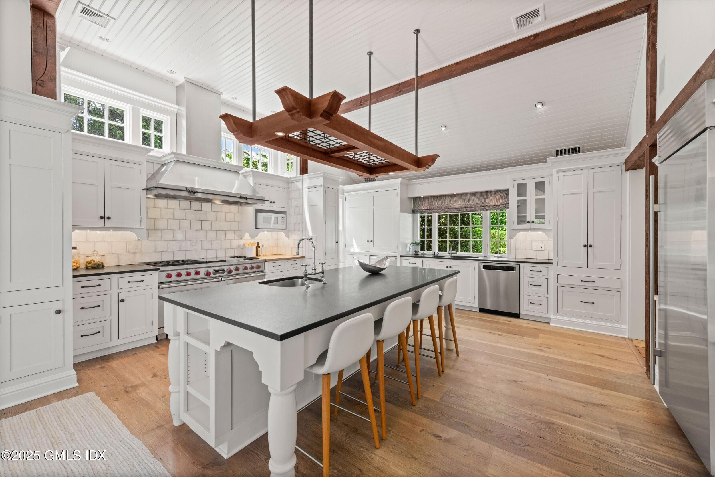 945 Oenoke Ridge New Canaan, CT 06840 - Photo 29 of 94 a kitchen with stainless steel appliances granite countertop a stove a refrigerator a oven a white with a dining table and chairs with wooden floor