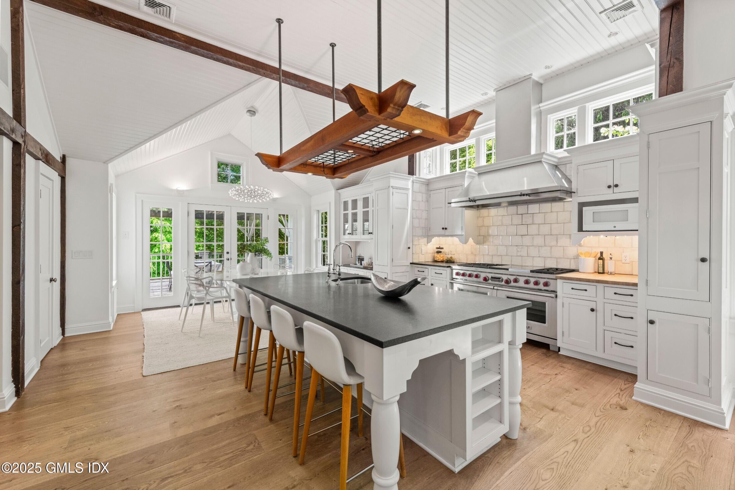 945 Oenoke Ridge New Canaan, CT 06840 - Photo 30 of 94 a kitchen with stainless steel appliances granite countertop a stove a sink dishwasher and a dining table with wooden floor