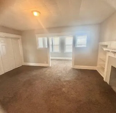 an empty room with a fireplace and window