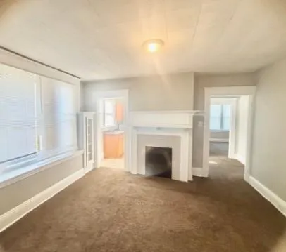 a view of an empty room with a fireplace and a window