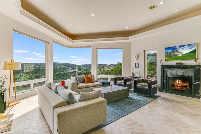 a living room with furniture a fireplace and floor to ceiling windows
