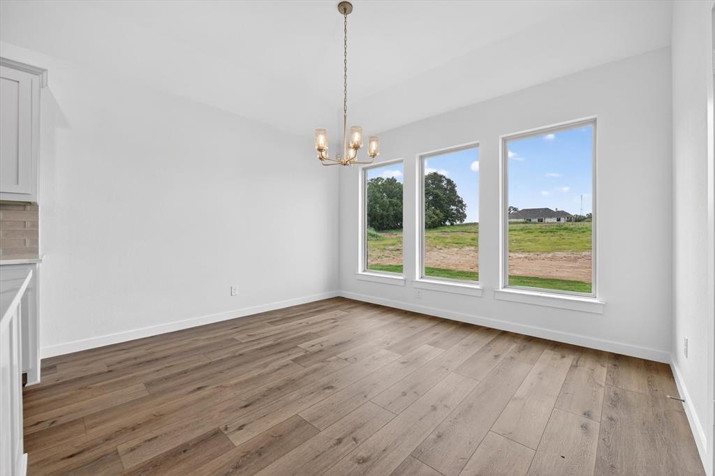 416 McAlpine Drive Springtown, TX 76082 - Photo 12 of 40 Spacious room featuring wood-finish flooring, a contemporary chandelier, and three large windows