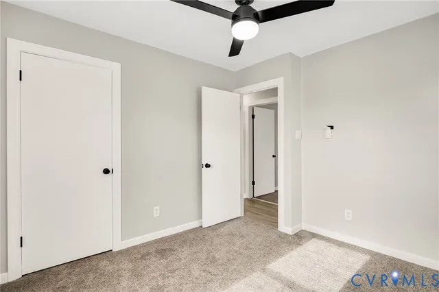 a view of an empty room and chandelier fan
