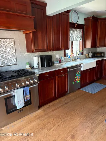 a kitchen with stainless steel appliances granite countertop a stove a sink dishwasher and a microwave oven with cabinets