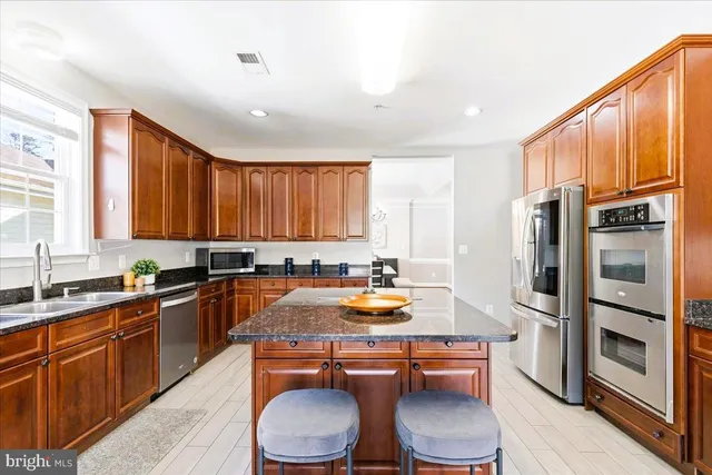 a kitchen with stainless steel appliances a stove a sink dishwasher a refrigerator and cabinets with wooden floor