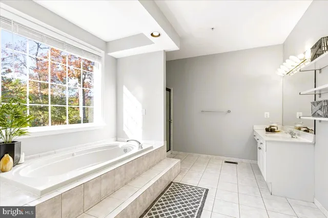 a bathroom with a tub a sink and a large window