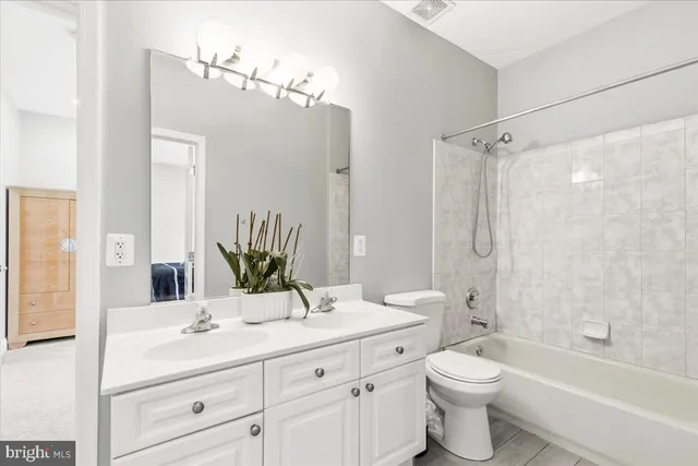 a bathroom with a double vanity sink toilet mirror and bathtub