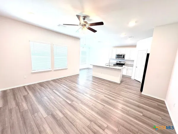 a view of empty room with wooden floor and fan