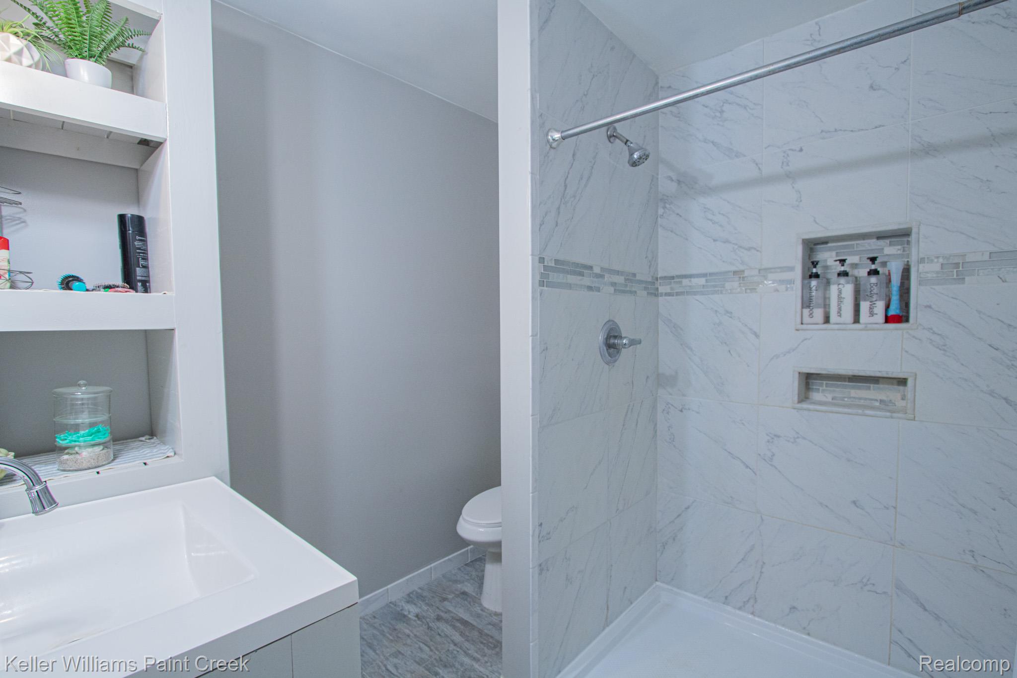 625 Howell Road Allenton, MI 48002 - Photo 22 of 46 White shower stall with large format wall tiles, decorative accent tile band, and recessed shelving