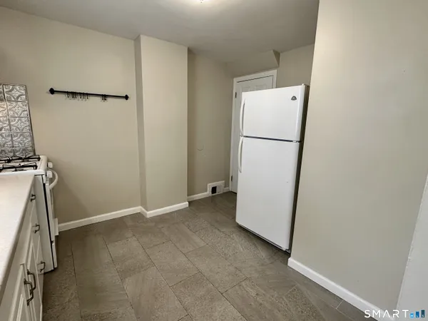 a view of a kitchen with refrigerator and white wall