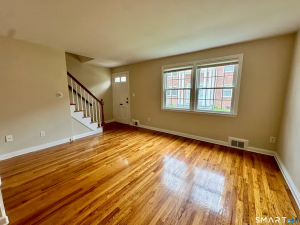 a view of an empty room with wooden floor and a window