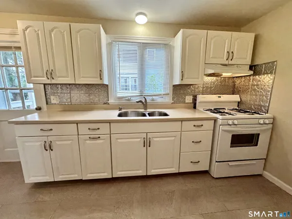 a kitchen with granite countertop white cabinets white stainless steel appliances and sink