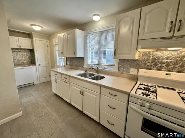 a kitchen with kitchen island granite countertop white cabinets and white appliances