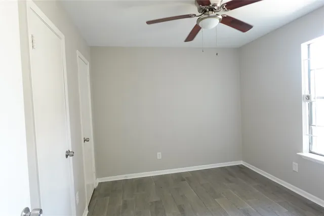 an empty room with a window and a fan