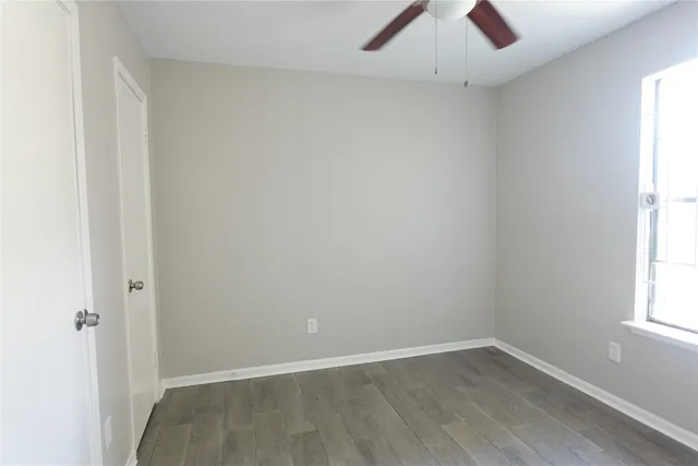 an empty room with a window and a ceiling fan