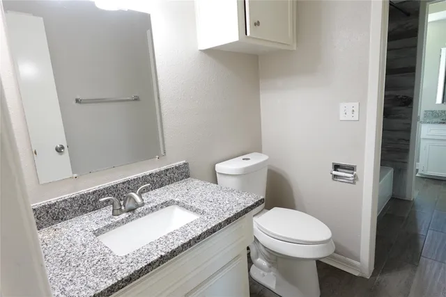 a bathroom with a granite countertop toilet sink and mirror