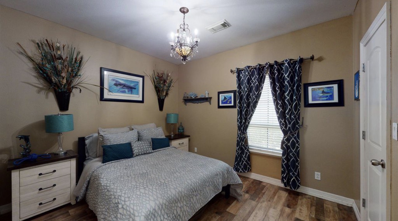104 Mockingbird Lane Bridge City, TX 77611 - Photo 18 of 27 a spacious bedroom with bed and a chandelier