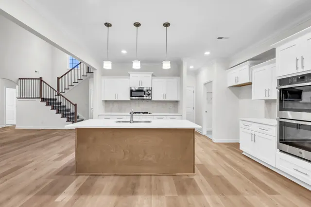 a large kitchen with stainless steel appliances kitchen island granite countertop a sink a stove and a wooden floors