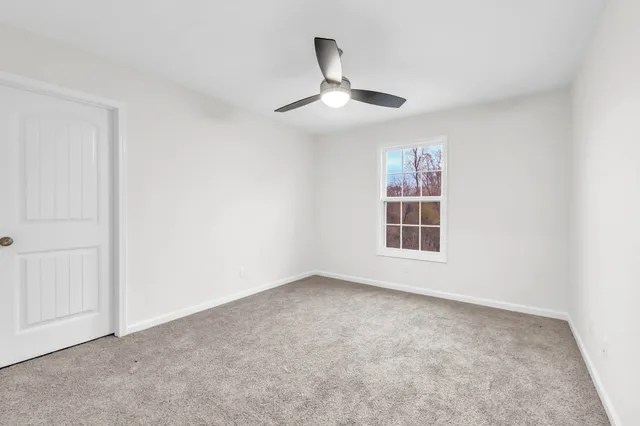an empty room with a ceiling fan and a window