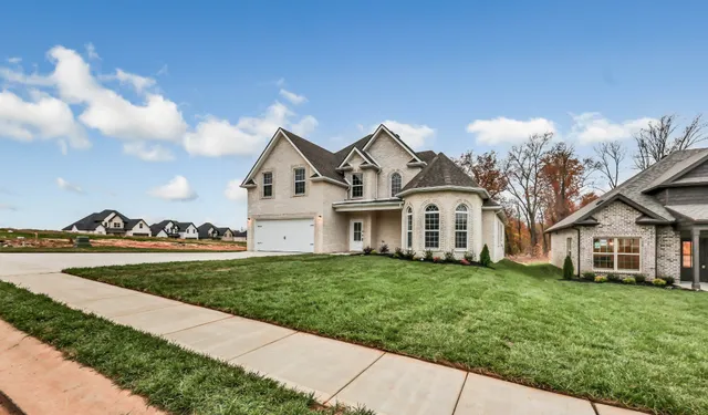 a front view of a house with a garden and trees